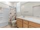 Bright bathroom features a vanity with light wood cabinets, a neutral countertop and a shower over tub with a beach-themed curtain at 24580 N 144Th Ave, Surprise, AZ 85387
