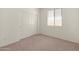 Empty bedroom with neutral carpet, white walls, a window with blinds, a closet with sliding doors, and electrical outlets at 24580 N 144Th Ave, Surprise, AZ 85387