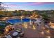 Resort style backyard showcasing the pool with waterfall, spa, lounge seating, outdoor kitchen, and fireplace at 30330 N 77Th Pl, Scottsdale, AZ 85266