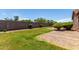 Private backyard featuring lush green grass, mature trees, gravel, and a block fence at 40275 W Art Pl, Maricopa, AZ 85138