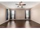 The large living room features hardwood floors, and large windows with curtains and blinds at 40275 W Art Pl, Maricopa, AZ 85138