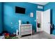 room with bright blue walls, a dresser, and a view into an adjacent room at 40441 W Hillman Dr, Maricopa, AZ 85138
