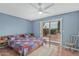 A cozy bedroom has blue walls, ceiling fan, and sliding door access to the patio with outdoor landscaping at 4229 E Pearce Rd, Phoenix, AZ 85044