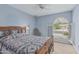 Comfortable bedroom with large window, ceiling fan, and neutral carpet is complemented by a dark wooden bed frame and a quilt at 4229 E Pearce Rd, Phoenix, AZ 85044