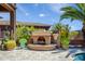 An outdoor fireplace surrounded by lush greenery in a backyard setting at 42293 W Good Vibrations Ln, Maricopa, AZ 85138