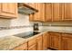 Modern kitchen featuring a sleek cooktop and wooden cabinets with granite counters at 42293 W Good Vibrations Ln, Maricopa, AZ 85138