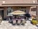 Covered patio with an outdoor dining area, grill, and landscaped plants at 42293 W Good Vibrations Ln, Maricopa, AZ 85138