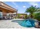 A backyard with a refreshing pool, outdoor dining area, and cozy fireplace at 42293 W Good Vibrations Ln, Maricopa, AZ 85138