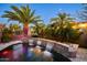 A lush backyard highlighting a beautiful pool with a triple waterfall feature surrounded by palms at 42293 W Good Vibrations Ln, Maricopa, AZ 85138