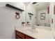 Bathroom vanity with a white sink, warm wood cabinets, and wall-mounted shelves at 6853 S Roosevelt St, Tempe, AZ 85283