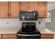 Close-up of the black stove, microwave, and wood cabinets in the kitchen at 6853 S Roosevelt St, Tempe, AZ 85283