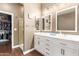 Well-lit bathroom with dual sinks, white cabinetry, and a glass-enclosed shower with a walk-in closet at 7445 E Eagle Crest Dr # 1061, Mesa, AZ 85207