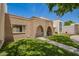 Exterior of a townhome featuring brick and beige facade, green lawn, and arched front entry at 7808 E Lewis Ave, Scottsdale, AZ 85257