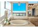 Bright bathroom featuring a soaking tub, a large window, and tiled countertops at 10772 E Running Deer Trl, Scottsdale, AZ 85262