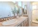Bright bathroom featuring dual sinks, natural stone counters, and a walk-in shower at 10772 E Running Deer Trl, Scottsdale, AZ 85262