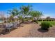 A park bench under shade trees on a gravel path is surrounded by manicured landscape and grass at 10956 E Thunderbolt Ave, Mesa, AZ 85212