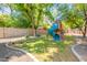 Lush backyard featuring a play structure with a blue slide, mature trees, and a concrete and gravel border at 1110 W Heatherbrae Dr, Phoenix, AZ 85013