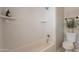 Bright white tiled shower and tub combination, complemented by stylish fixtures and shelving at 1110 W Heatherbrae Dr, Phoenix, AZ 85013