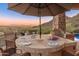 Charming outdoor dining area with a large stone table, grill, and panoramic mountain views at 11550 E Paradise Ln, Scottsdale, AZ 85255
