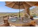 Outdoor dining area under a large umbrella, with pool views and outdoor grill for entertaining guests at 11550 E Paradise Ln, Scottsdale, AZ 85255