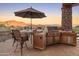 Outdoor kitchen and dining area with stunning desert sunset views provide relaxation and entertainment opportunities at 11550 E Paradise Ln, Scottsdale, AZ 85255