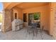 Cozy covered patio featuring a stone accent wall, BBQ, and seating area for relaxing and outdoor enjoyment at 11550 E Paradise Ln, Scottsdale, AZ 85255