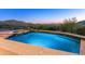 Inviting pool featuring pristine blue tile, stone accents, and stunning mountain views at dusk at 11550 E Paradise Ln, Scottsdale, AZ 85255