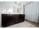 This bathroom has a double sink vanity with a white countertop, dark cabinetry, and a shower with a glass door at 15424 N 22Nd Ln, Phoenix, AZ 85023