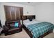 Bedroom featuring a queen-size bed with a green-and-gray plaid comforter, next to a leather armchair at 15424 N 22Nd Ln, Phoenix, AZ 85023