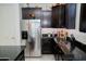 Well-lit kitchen featuring stainless steel refrigerator, dark cabinets, and black countertops for a modern touch at 15424 N 22Nd Ln, Phoenix, AZ 85023