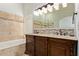 Bathroom featuring a soaking tub, double vanity with drawers, and tiled walls at 15430 N 19Th Way, Phoenix, AZ 85022