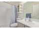 A clean bathroom with a shower-tub combo, corner shelving, and a white vanity at 15430 N 19Th Way, Phoenix, AZ 85022