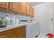 A laundry room with wooden cabinets, white appliances, and storage options at 15430 N 19Th Way, Phoenix, AZ 85022