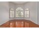 Bright, empty living room featuring beautiful hardwood floors, large arched windows, and white shutters at 15430 N 19Th Way, Phoenix, AZ 85022