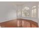 Bright, empty living room featuring beautiful hardwood floors, large arched windows, and white shutters at 15430 N 19Th Way, Phoenix, AZ 85022