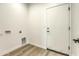 Bright laundry area with wood-look floors, utility connections, and a sleek white door at 16025 E Rancho Laredo Dr, Scottsdale, AZ 85262