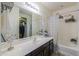 Bright bathroom with dark vanity, decorative mirror, and bathtub shower at 19365 N Pietra Dr, Maricopa, AZ 85138