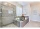 Bathroom with glass-enclosed shower, soaking tub, and stylish neutral tile at 1952 W Yellowstone Way, Chandler, AZ 85248