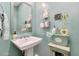Charming powder room with a pedestal sink, decorative mirror, and stylish storage shelves and accessories at 1952 W Yellowstone Way, Chandler, AZ 85248