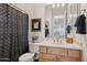 Bathroom featuring a toilet, wooden vanity with gold fixtures, a black and white shower curtain, and framed art at 1958 W Legends Way, Anthem, AZ 85086