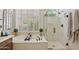 Bright bathroom with a glass-enclosed shower, bathtub and plantation shutters at 1958 W Legends Way, Anthem, AZ 85086