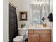 Bathroom featuring a toilet, wooden vanity with gold fixtures, a black and white shower curtain, and framed art at 1958 W Legends Way, Anthem, AZ 85086