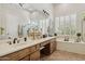 Bright bathroom with a large mirror, double sinks, a bathtub beneath shuttered windows, and tiled flooring at 1958 W Legends Way, Anthem, AZ 85086