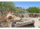 Resort-style outdoor living area with fireplace, comfortable seating, and beautiful landscaping at 1958 W Legends Way, Anthem, AZ 85086
