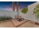 Backyard patio featuring a fire pit and desert landscaping against a white privacy wall at sunset at 2018 E Balboa Dr, Tempe, AZ 85282