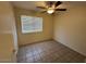 Well-lit bedroom featuring a ceiling fan, tiled flooring, and large window providing ample natural light at 21192 N 80Th Ln, Peoria, AZ 85382