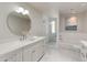 Bright bathroom features a modern vanity, round mirror, and separate tub and glass shower at 23240 N Country Club Trl, Scottsdale, AZ 85255