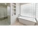 Bathroom with soaking tub and shower, featuring a large glass block window for natural light at 23240 N Country Club Trl, Scottsdale, AZ 85255