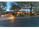 Inviting single-story home featuring desert landscaping, mature trees, and a well-lit driveway at 23240 N Country Club Trl, Scottsdale, AZ 85255