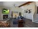 Comfortable living room boasts a fireplace, ceiling fan, and plush seating, with stair access nearby at 25609 N Forest Rd # 13, Rio Verde, AZ 85263